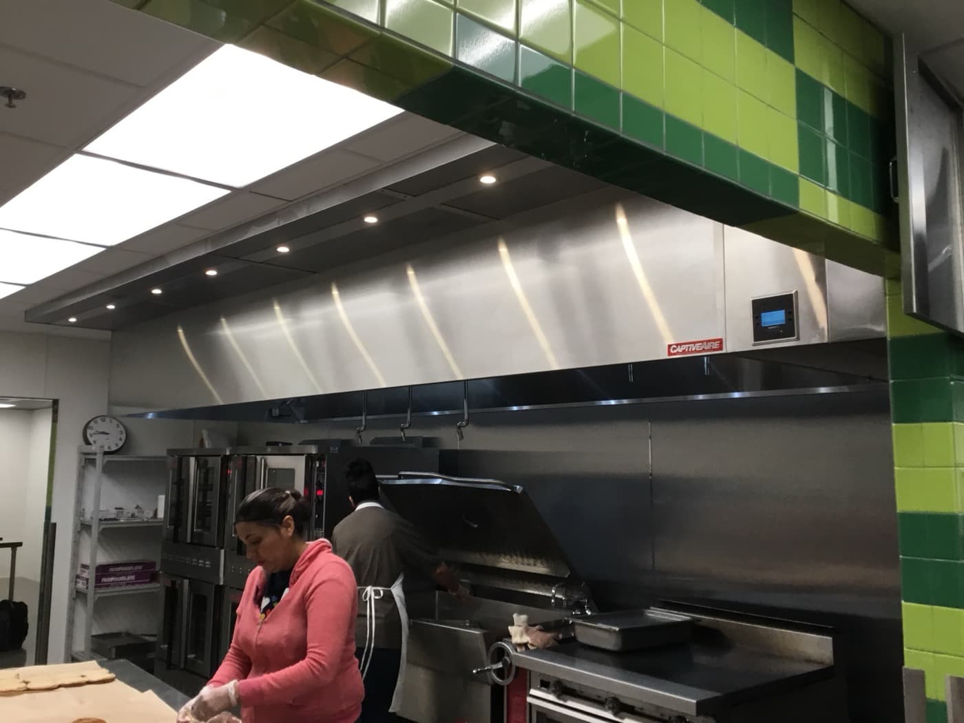 CaptiveAire hood over active commercial kitchen cooking line with staff