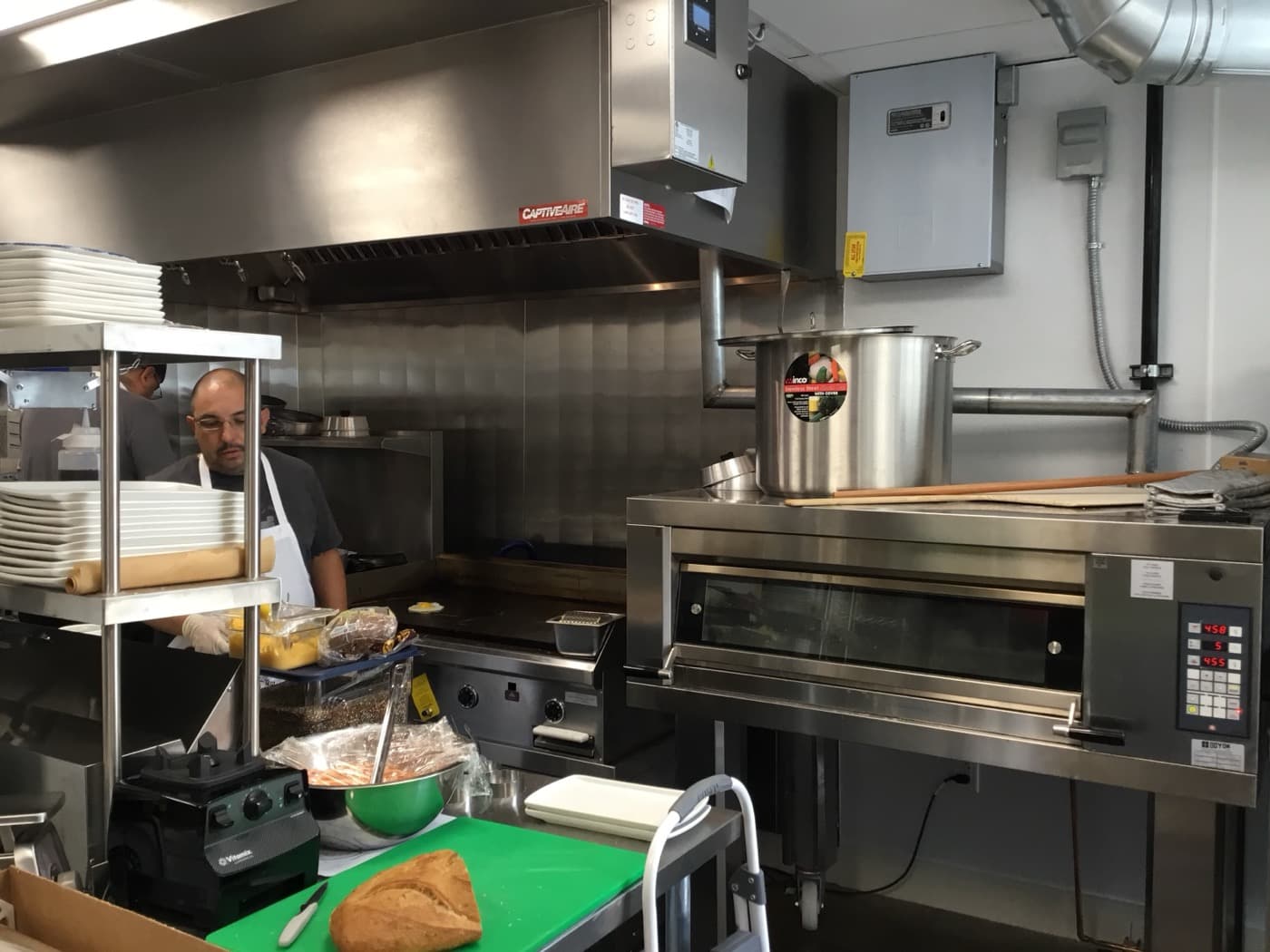 Cook working in commercial kitchen under CaptiveAire ventilation hood