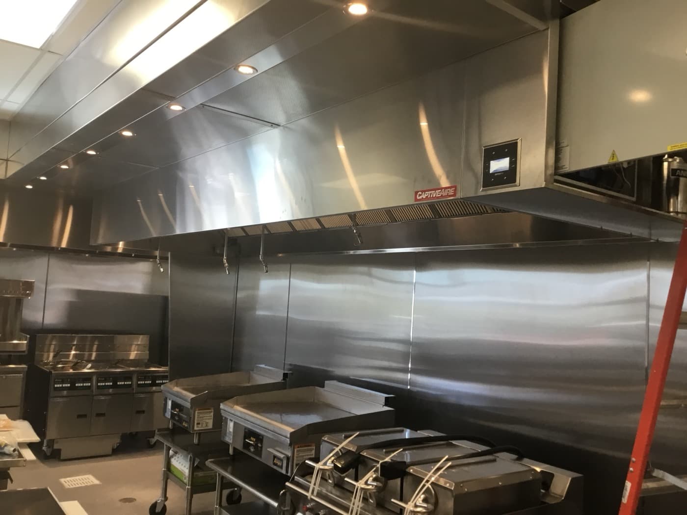 Full commercial kitchen ventilation installation with cooking equipment
