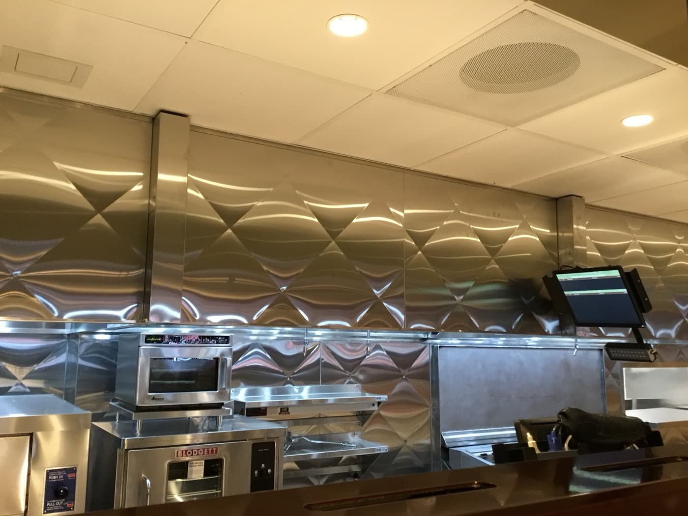 High-volume commercial cooking line beneath ventilation hoods
